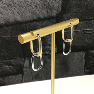 A pair of two-tone gold chain link drops displayed on a stand, with the top part in yellow gold and the bottom part in silver.