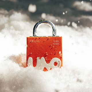Red lock with 'lunode50' engraved on it, partially submerged in snow.