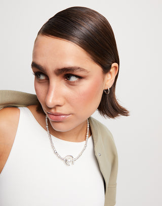 Woman wearing a necklace with a plain background