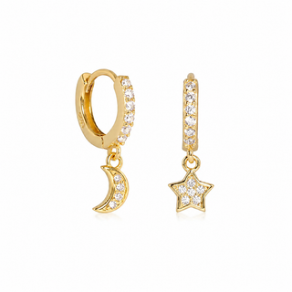 A pair of gold huggie hoop earrings with clear cubic zirconia stones, featuring a dangling crescent moon on one earring and a dangling star on the other, set against a plain white background.