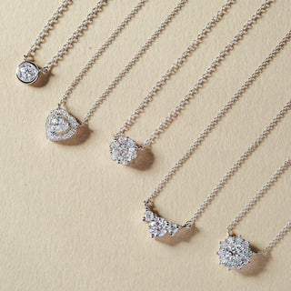 Silver necklaces with various pendants on a beige background