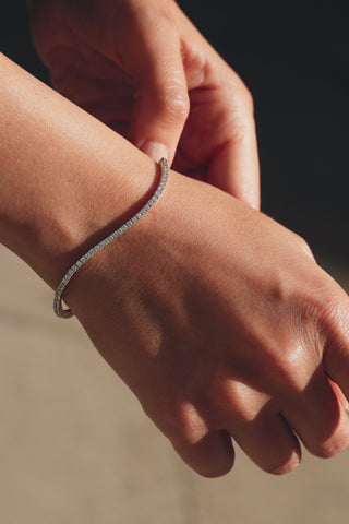 Close-up of a hand wearing a bracelet on a neutral background