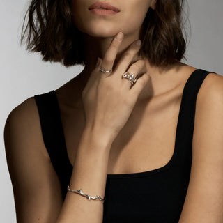 Woman wearing a black top with silver jewelry on a neutral background
